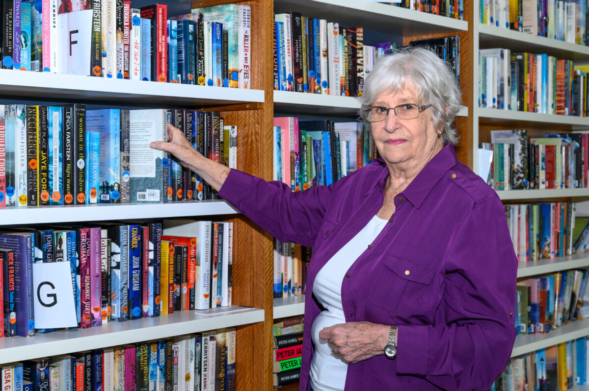Barwarre Gardens resident Gail Ingleby stands in front of library shelves selecting a book.